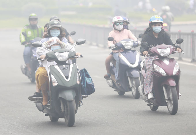 Người lớn và trẻ em đều mặc áo ấm, đeo khẩu trang khi ra đường trong sương mù dày đặc ở TP HCM, sáng 24/12/2020. Ảnh: Hữu Khoa.