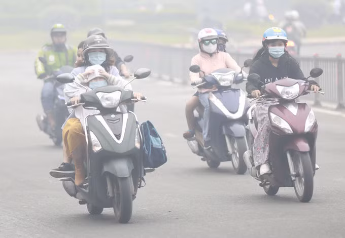 Người lớn và trẻ em đều mặc áo ấm, đeo khẩu trang khi ra đường trong sương mù dày đặc ở TP HCM, sáng 24/12/2020. Ảnh: Hữu Khoa.