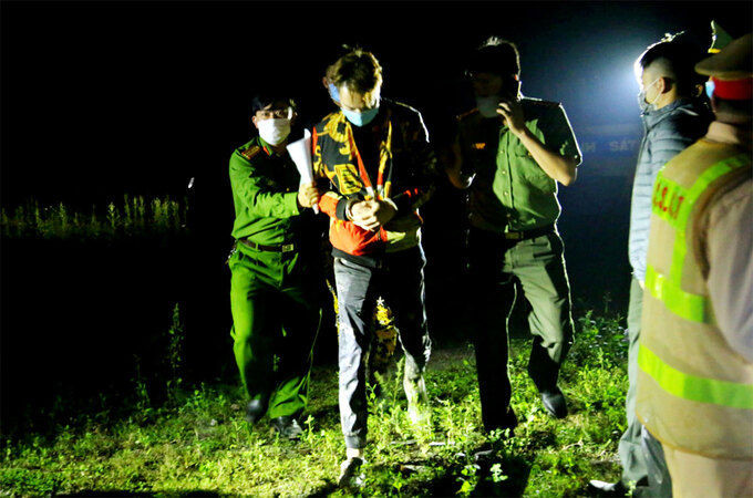 Một người Trung Quốc (thứ hai, từ trái sang) bị cảnh sát khống chế, tói 17/3. Ảnh: Hùng Cường