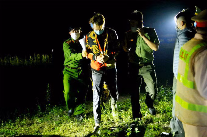 Một người Trung Quốc (thứ hai, từ trái sang) bị cảnh sát khống chế, tói 17/3. Ảnh: Hùng Cường