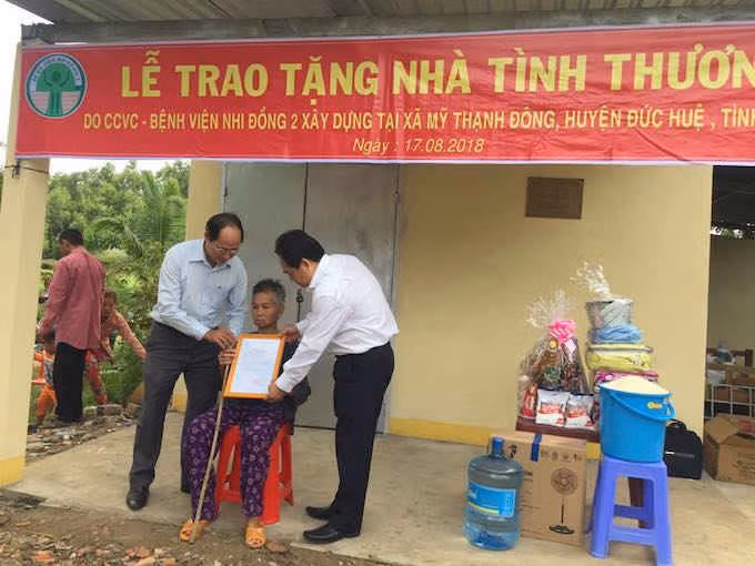 BS.CK II Trịnh Hữu Tùng – giám đốc Bệnh viện Nhi Đồng 2 TPHCM (tay phải) và ông Lê Văn Nên - Phó chủ tịch UBND huyện Đức Huệ, tỉnh Long An trao quyết định nhà tình thương cho bà Võ Thị Nời.