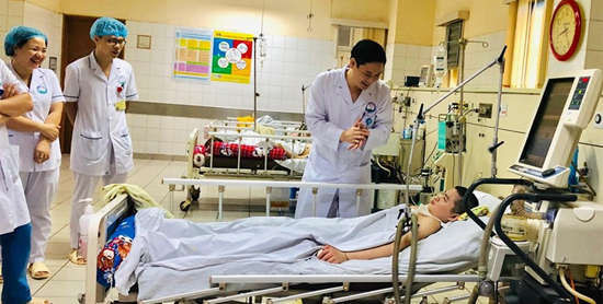 Các y bác sĩ đứng xung quanh giường bệnh cười hạnh phúc khi bệnh nhi hồi tỉnh. Ảnh do bác sĩ cung cấp.