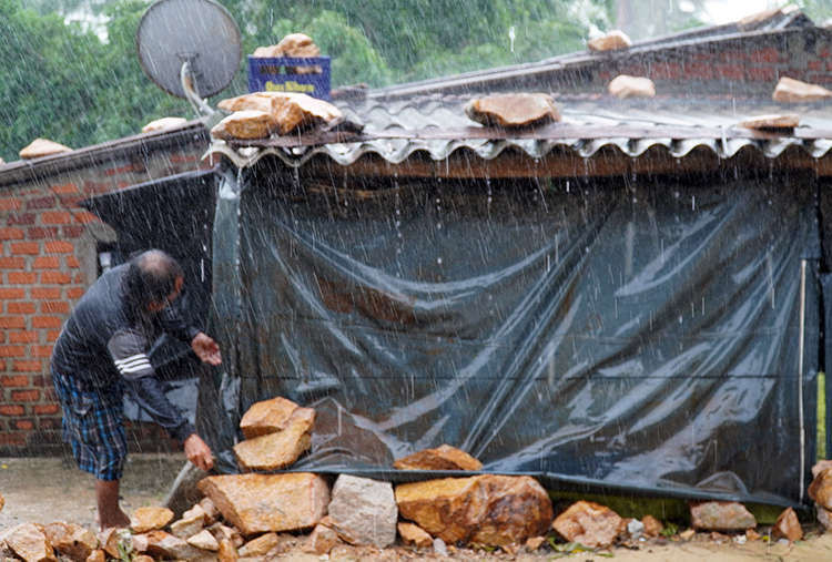 Ông Trần Út, người dân xã Xuân Cảnh (thị xã Sông Cầu) đội mưa ra ghè đá lại căn nhà gần biển. Ảnh: Việt Quốc.