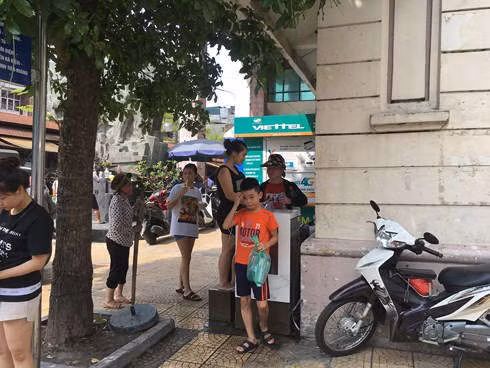 Tại trụ nước miễn phí ở chợ Đồng Xuân, rất đông người xếp hàng chờ lấy nước.