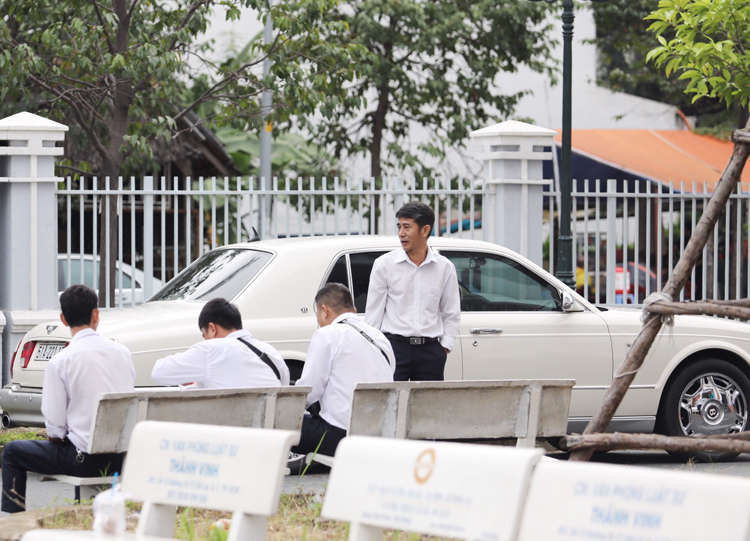 Ông Vũ ngồi trong ôtô trắng, xung quanh có 6 người mặc đồng phục. Ảnh: Thành Nguyễn.