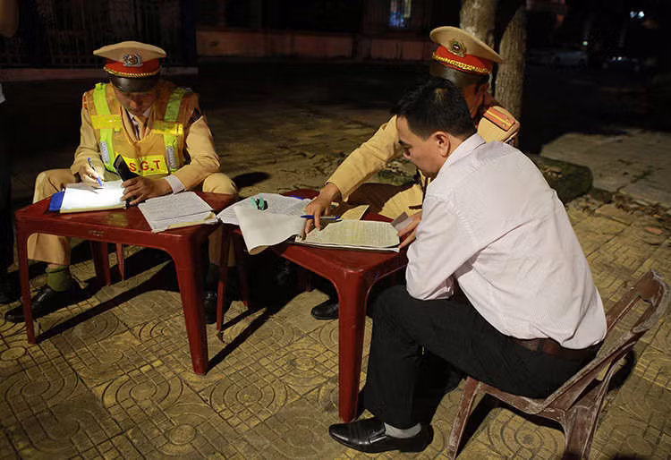 Nam tài xế được yêu cầu ký vào biên bản vi phạm. Ảnh: Nguyễn Hải.