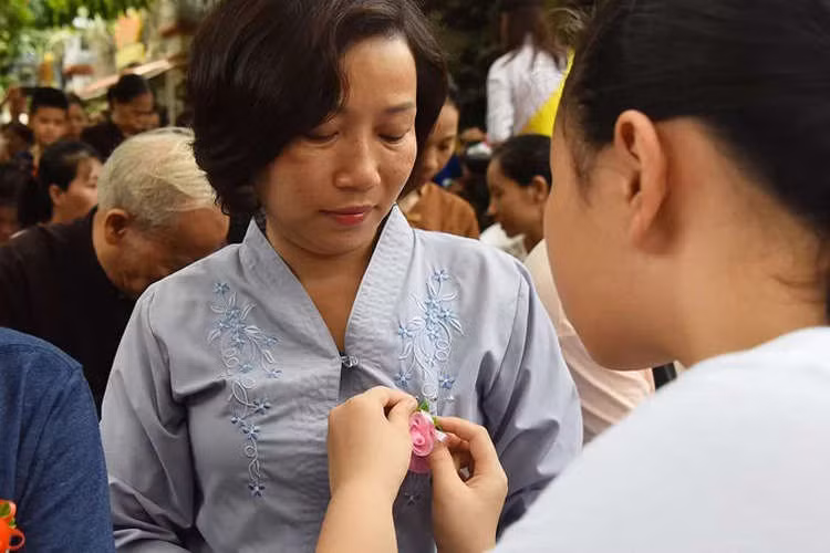 Phật tử nhí cài hoa hồng lên áo cha mẹ trong lễ Vu Lan tại chùa Văn Trì (Hà Nội) năm 2018. Ảnh: Giang Huy