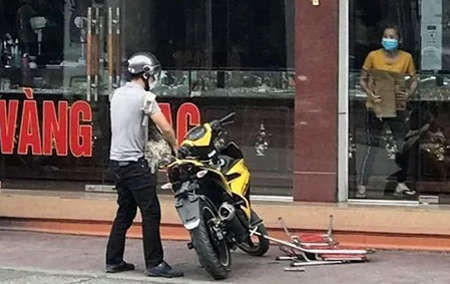 Ôm ba lô đựng tiền định lên xe máy tẩu thoát, nhưng tên cướp đánh rơi bọc tiền và bị một phụ nữ trong tiệm vàng lao ra giật lại. Ảnh: CTV