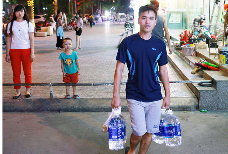 Anh Hà Quốc Tú (chung cư HH2C Linh Đàm) mua nước đóng chai về nấu ăn. Ảnh: Tất Định.