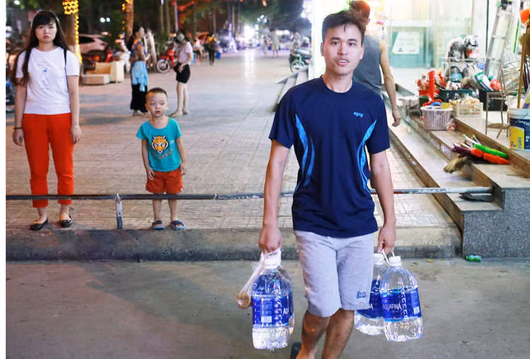 Anh Hà Quốc Tú (chung cư HH2C Linh Đàm) mua nước đóng chai về nấu ăn. Ảnh: Tất Định.