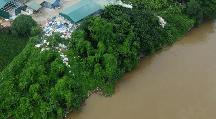 Rác thải nhựa quá nhiều, chất đống đầy cả một nhà chứa, thậm chí rác còn tràn xuống cả mép bờ sông Hồng.