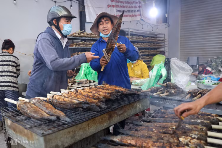 Nhiều người vào hẳn trong nhà chọn cá lóc nướng. Giá sỉ cao hơn mọi năm nên cá nướng cũng tăng lên 180.000-240.000 đồng một con, tuỳ kích cỡ - Ảnh:vnexpress Nhiều người vào hẳn trong nhà chọn cá lóc nướng. Giá sỉ cao hơn mọi năm nên cá nướng cũng tăng lên 180.000-240.000 đồng một con, tuỳ kích cỡ - Ảnh:vnexpress