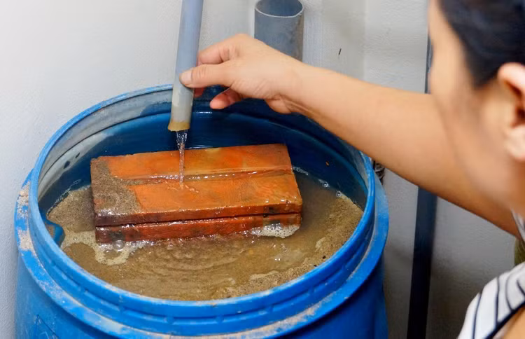 Không có nước máy, chồng chị Tần phải “chế” bể lọc nước giếng khoan bằng thùng sơn cũ, cát, trấu…