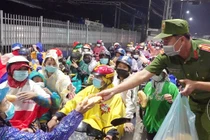 Công an phát thức ăn va nước uống cho người dân tự ý về quê. Ảnh: Tiến Tầm.