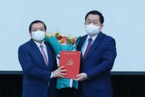 Ông Nguyễn Trọng Nghĩa trao quyết định và tặng hoa chúc mừng ông Lại Xuân Môn. 