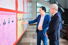 Ông Vũ Văn Tiến, Ủy viên Đoàn Chủ tịch, Trưởng Ban Tuyên giáo Cơ quan Ủy ban Trung ương MTTQ Việt Nam cùng cử tri xem thông tin người ứng cử