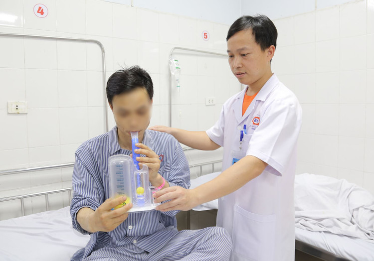 Bác sĩ khoa Ngoại hướng dẫn bệnh nhân tập thở bằng dụng cụ để tăng thông khí phổi, cải thiện hô hấp - Ảnh BVCC