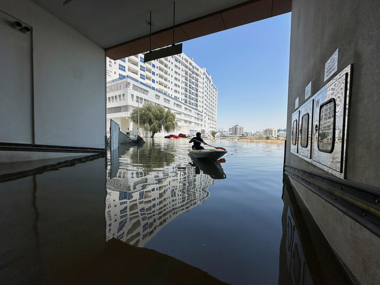 A volunteer uses a kayak during a rescue operation through a road flooded due to heavy rains in Dubai