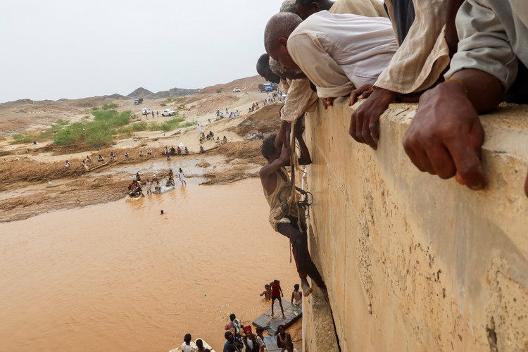 A survivor harnessed to a rope is being helped to climb a wall, following devastating floods, in South Tokar, Red Sea State, Sudan
