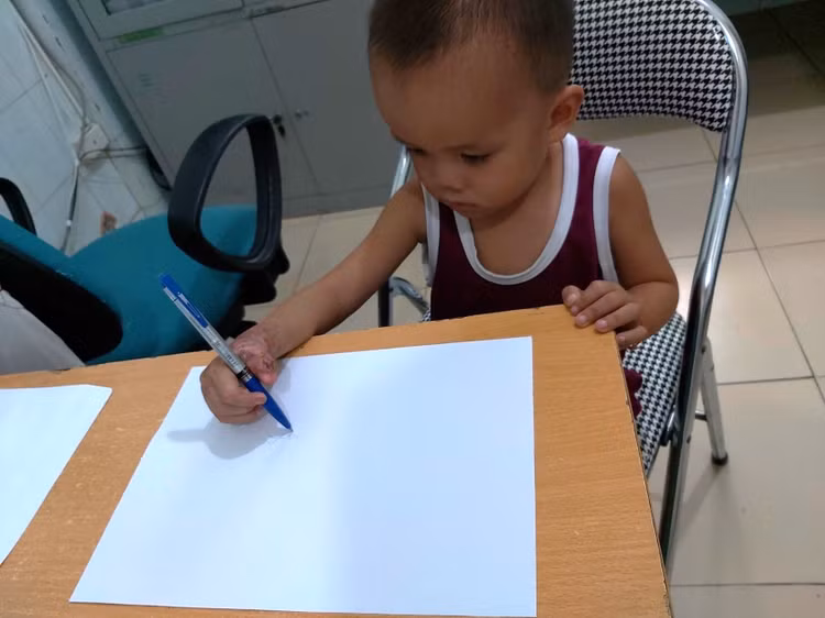 Tay bé đã có thể cầm bút viết - Ảnh BVCC