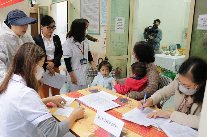 Cán bộ y tế Trạm Y tế phường Láng Hạ tiếp đón người dân đưa trẻ đến uống vitamin A.