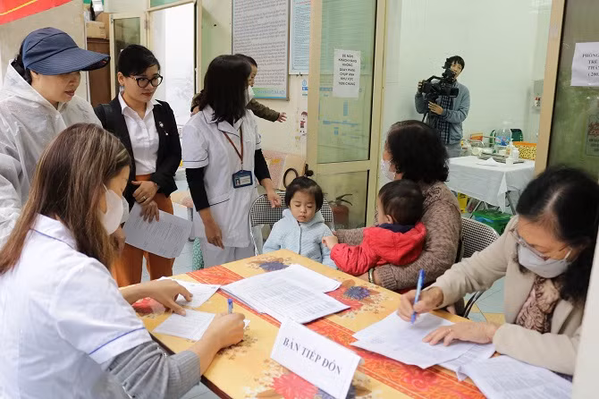 Cán bộ y tế Trạm Y tế phường Láng Hạ tiếp đón người dân đưa trẻ đến uống vitamin A.