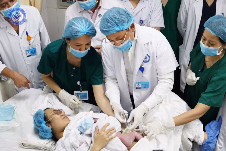 GS.TS Nguyễn Duy Ánh cắt dây rốn cho em bé sinh đầu tiên năm 2025 tại bệnh viện - Ảnh BVCC