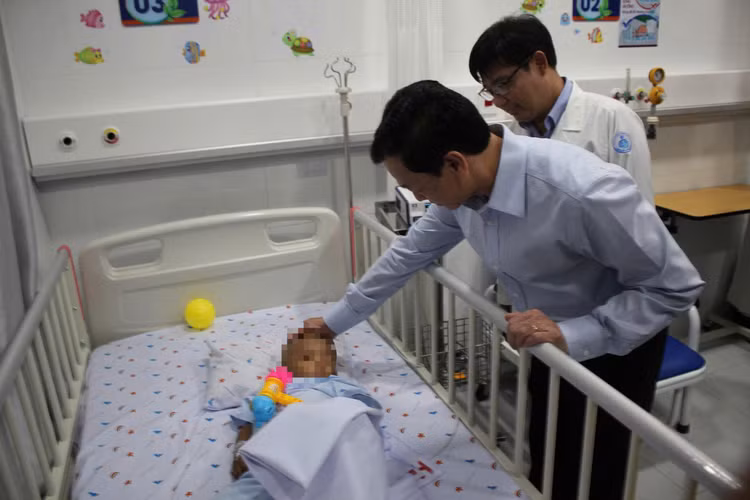 Thứ trưởng Nguyễn Tri Thức thăm hỏi em bé bị bạo hành - Ảnh Đỗ Bá