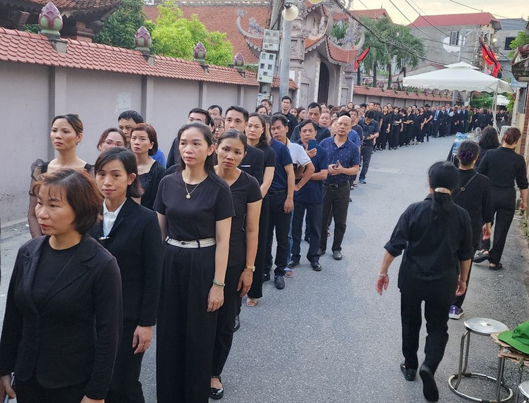 Trời dần tối, hàng dài người vẫn xếp hàng nối theo nhau vào nhà văn hóa thôn Lại Đà, xã Đông Đội, huyện Đông Anh để viếng Tổng Bí thư Nguyễn Phú Trọng. (Ảnh: Thiên Tuấn)
