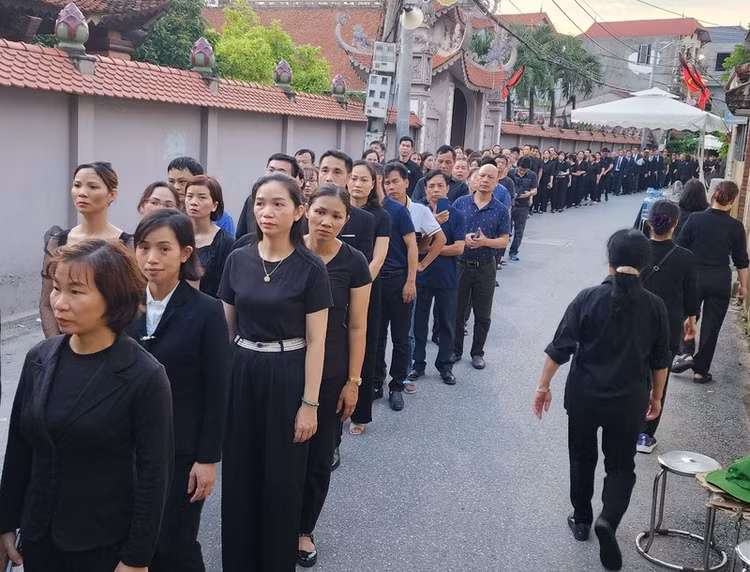 Trời dần tối, hàng dài người vẫn xếp hàng nối theo nhau vào nhà văn hóa thôn Lại Đà, xã Đông Đội, huyện Đông Anh để viếng Tổng Bí thư Nguyễn Phú Trọng. (Ảnh: Thiên Tuấn)
