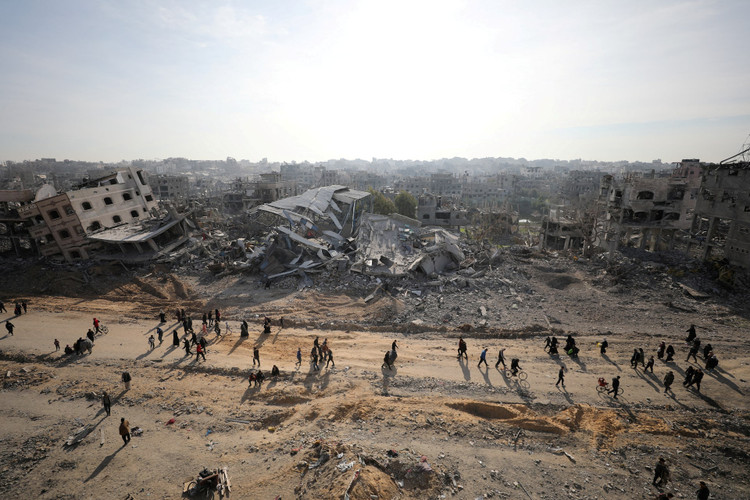 Displaced Palestinians walk past the rubble as they attempt to return to their homes, in the northern Gaza Strip