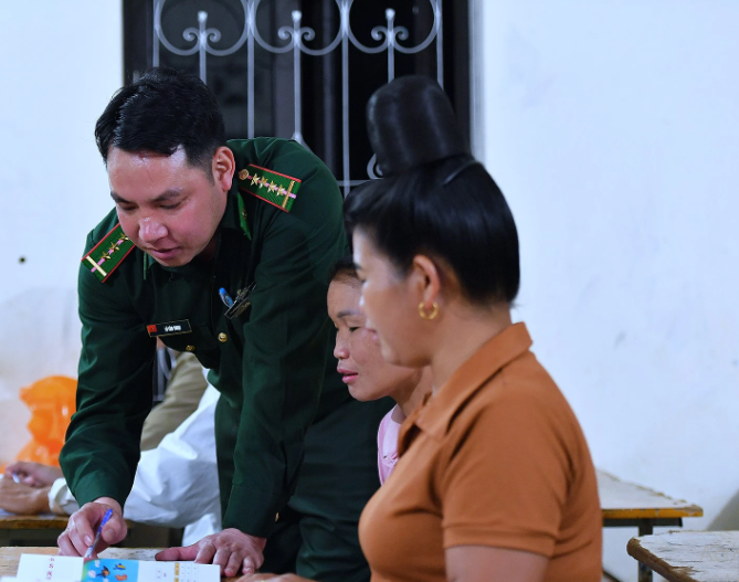 Đại úy kiêm thầy giáo Lò Văn Thoại trở thành người bạn, người thầy từng ngày kiên trì giúp bà con biết đọc chữ, viết tên. Ảnh Báo Nhân Dân