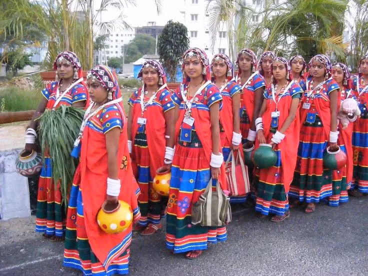 Trang phục truyền thống có hoa văn đơn giản nhưng nổi bật. Phụ nữ Santal thường mặc sari truyền thống với màu sắc tươi sáng, trong khi nam giới mặc dhoti hoặc trang phục đơn giản phù hợp với lao động nông nghiệp. Trang phục thường được kết hợp với vòng cổ, vòng tay và đồ trang sức kim loại đặc trưng. Ảnh: Pinterest.