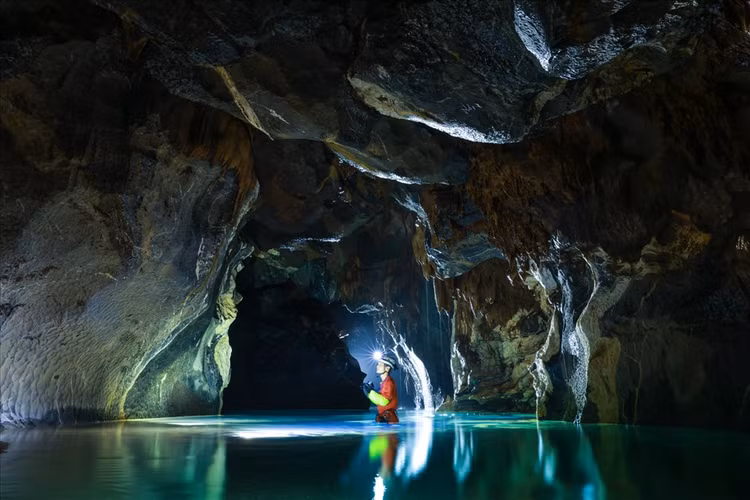 Để đến hang Va, đoàn phải đi bộ băng rừng, tiếp tục leo lên dốc rồi lại tụt xuống sâu. Đến miệng hang, các thành viên mang đai an toàn để bắt đầu tụt xuống. Từ đây, đoàn phải bơi, lội dưới dòng nước lạnh để tìm đến thác nước nằm ở cuối hang, cách miệng hang khoảng 1,7km. Ảnh: Ngô Trần Hải An