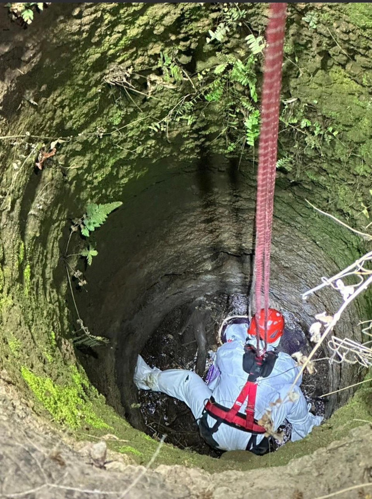 Một chiến sĩ đu dây xuống giếng sâu để trục vớt thi thể nạn nhân.