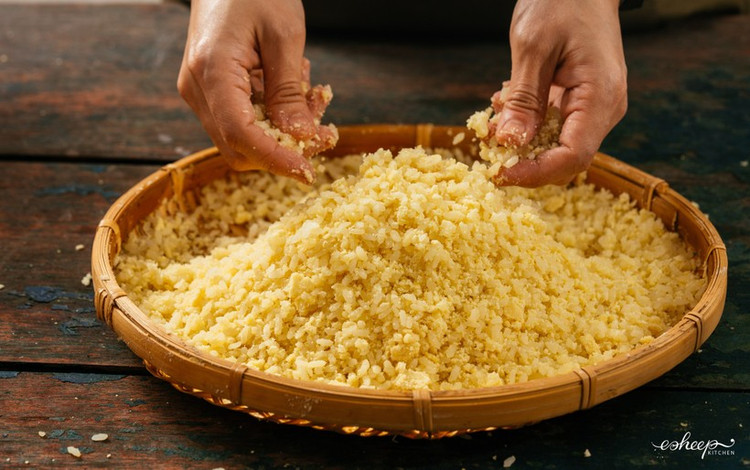 Sau khi đồ cho xôi chín cỡ 80% thì xới tơi rồi trút xôi ra cái nia tre, dàn đều cho nguội bớt. Sau đó trộn đường khi xôi vẫn còn nóng ấm. Phủ thêm lớp đỗ bào mỏng, vò lần hai nhẹ tay cho đỗ quyện lại cùng xôi. Ảnh giaoducthoidai