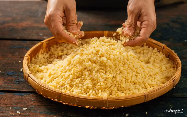 Sau khi đồ cho xôi chín cỡ 80% thì xới tơi rồi trút xôi ra cái nia tre, dàn đều cho nguội bớt. Sau đó trộn đường khi xôi vẫn còn nóng ấm. Phủ thêm lớp đỗ bào mỏng, vò lần hai nhẹ tay cho đỗ quyện lại cùng xôi. Ảnh giaoducthoidai