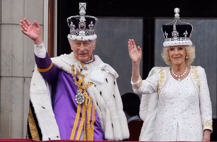 Vua Charles III và Hoàng hậu Camilla vẫy tay chào người dân từ ban công Cung điện Buckingham - nguồn: NPR