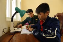 Chiến sỹ đồn Biên phòng Pa Thơm, tỉnh Điện Biên hướng dẫn cháu Quàng Trung Thành học bài sau giờ lên lớp. Ảnh: Phan Tuấn Anh/TTXVN