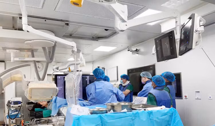 Ekip đang thực hiện đặt stent chuyển hướng dòng chảy qua túi phình - Ảnh BVCC Ekip đang thực hiện đặt stent chuyển hướng dòng chảy qua túi phình - Ảnh BVCC