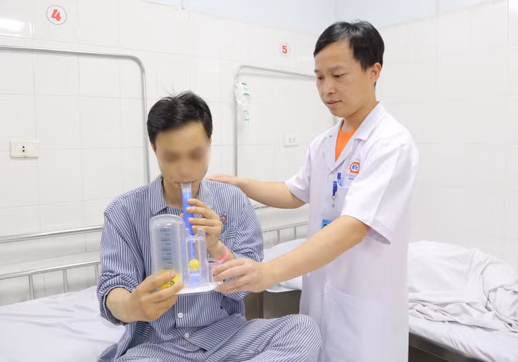 Bác sĩ khoa Ngoại hướng dẫn bệnh nhân tập thở bằng dụng cụ để tăng thông khí phổi, cải thiện hô hấp - Ảnh BVCC